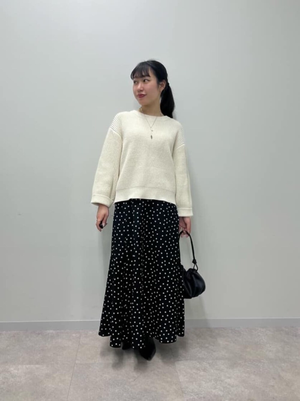ブラック系のスカート、ホワイト系のニット/セーターを着用したレディースの冬コーディネートの2枚目の写真