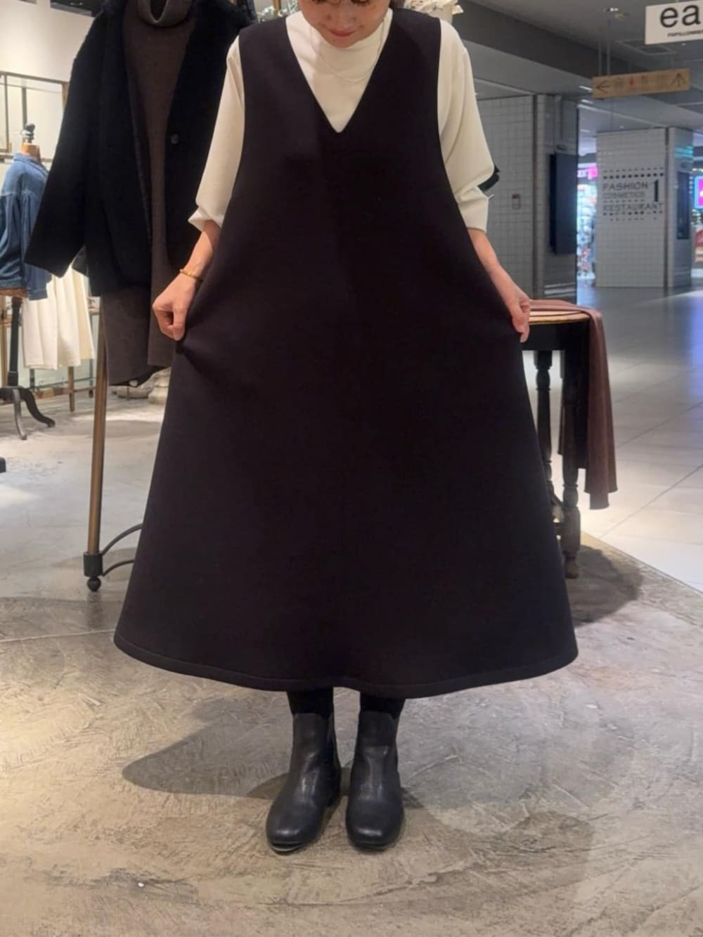 ホワイト系のシャツ/ブラウス、ブラック系のブーツ、ブラック系のジャンパースカートを着用したレディースの冬コーディネートの6枚目の写真