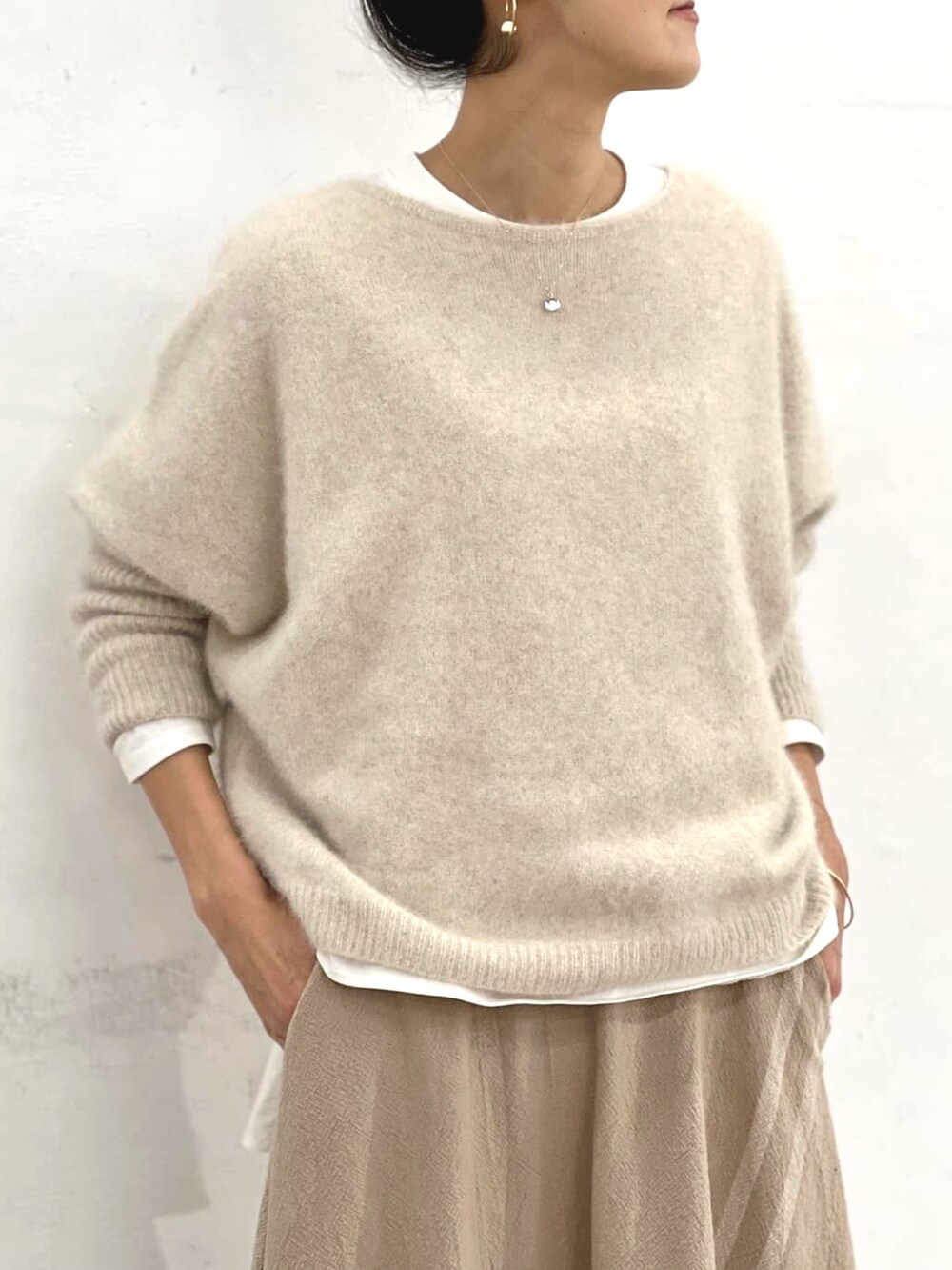 ホワイト系のニット/セーター、ホワイト系のTシャツ/カットソー、ベージュ系のスカートを着用したレディースの秋コーディネートの3枚目の写真