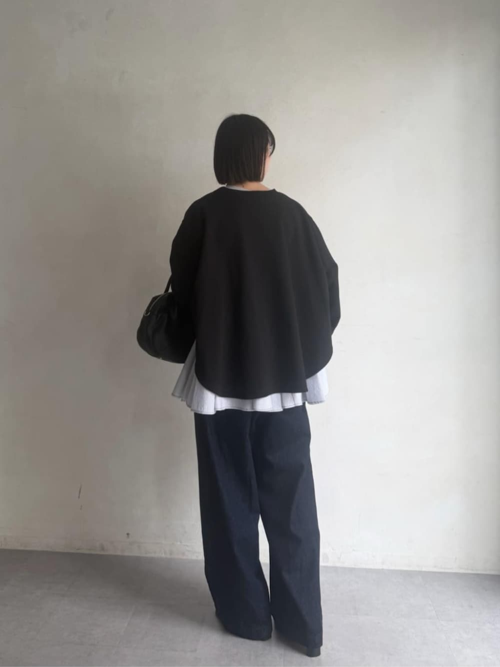 ブラック系のボストンバッグ、ブラック系のTシャツ/カットソー、ブルー系のデニムパンツを着用したレディースの冬コーディネートの5枚目の写真