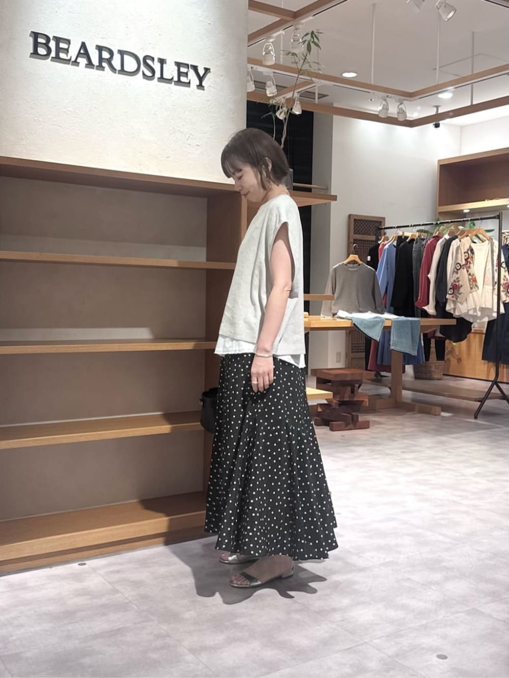 ブラック系のハンドバッグ、ブラック系のスカート、ベージュ系のシャツ/ブラウスを着用したレディースの春コーディネートの3枚目の写真