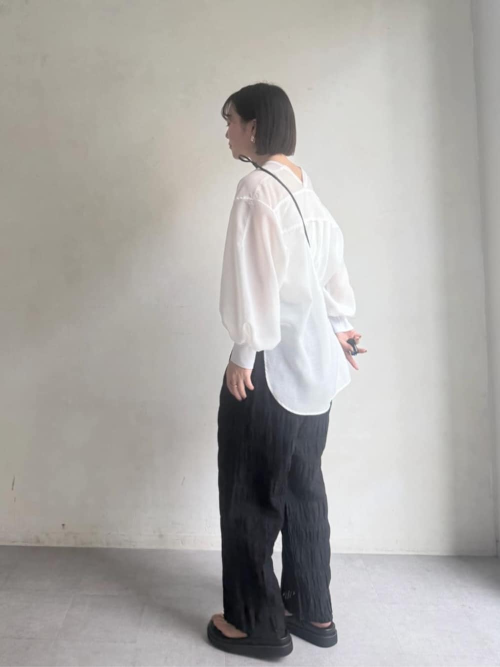 ブラック系のその他パンツ、ブラック系のサンダル、ホワイト系のシャツ/ブラウスを着用したレディースの冬コーディネートの3枚目の写真