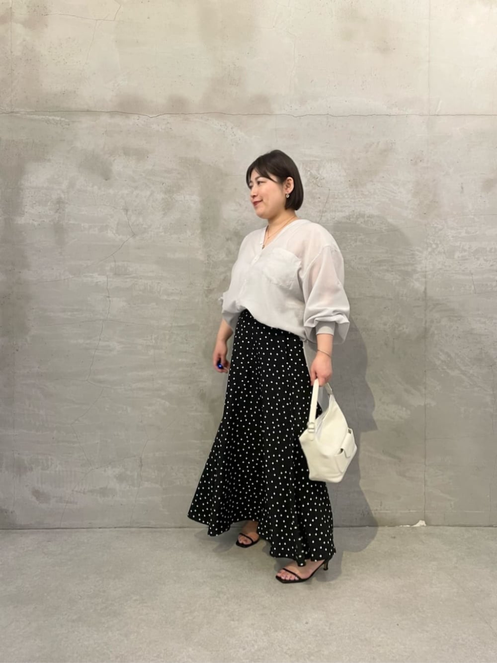 ブラック系のスカート、ホワイト系のトートバッグ、グレー系のシャツ/ブラウスを着用したレディースの冬コーディネートの2枚目の写真