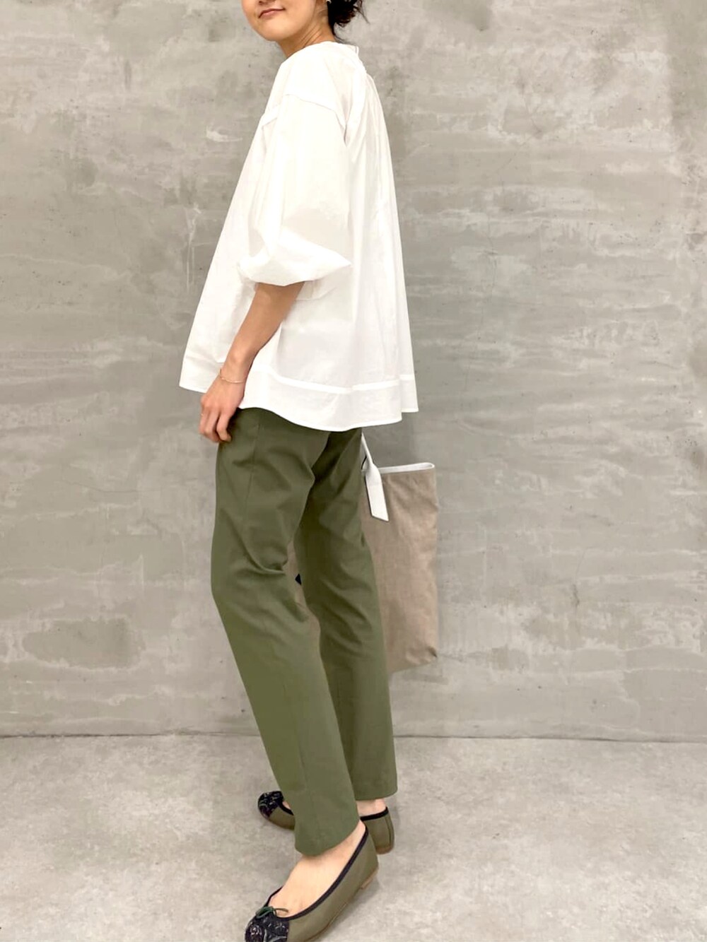 イエロー系のノーカラーコート、ホワイト系のシャツ/ブラウス、グリーン系のその他パンツを着用したレディースの春コーディネートの3枚目の写真