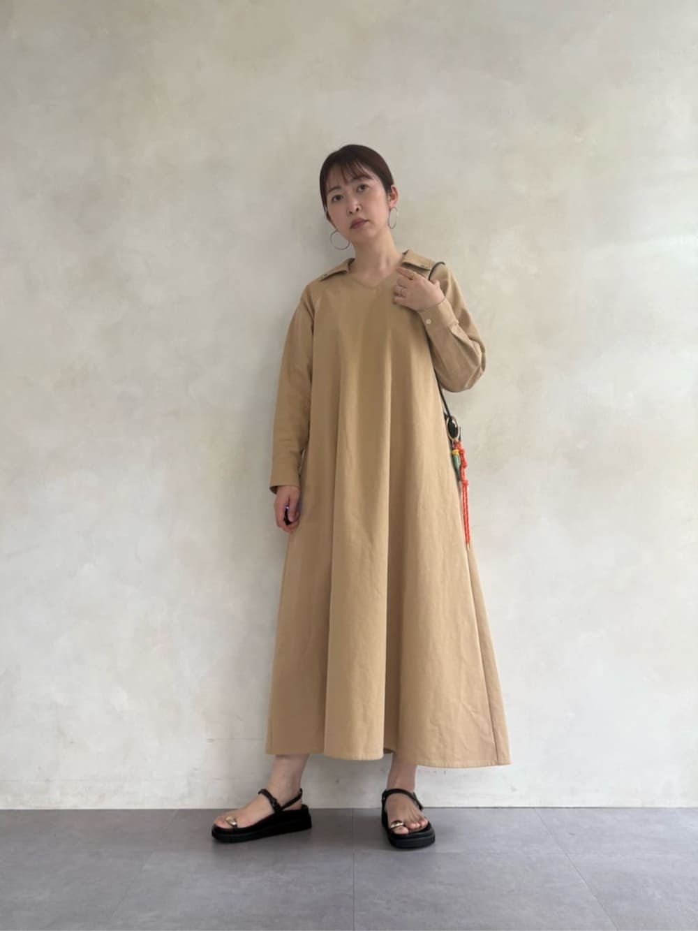 ブラック系のサンダル、ブラック系のショルダーバッグ、ベージュ系のワンピースを着用したレディースの春コーディネートの2枚目の写真