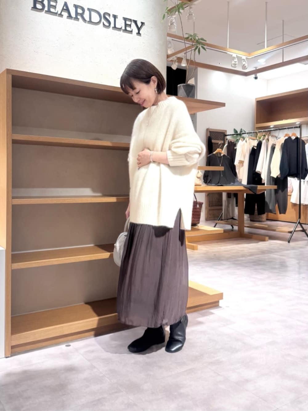 グレー系のボストンバッグ、ホワイト系のニット/セーター、ブラウン系のその他パンツを着用したレディースの冬コーディネートの2枚目の写真