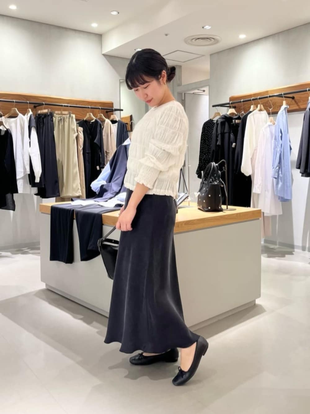 ブラック系のスカート、ブラック系のトートバッグ、ホワイト系のシャツ/ブラウスを着用したレディースの春コーディネートの8枚目の写真