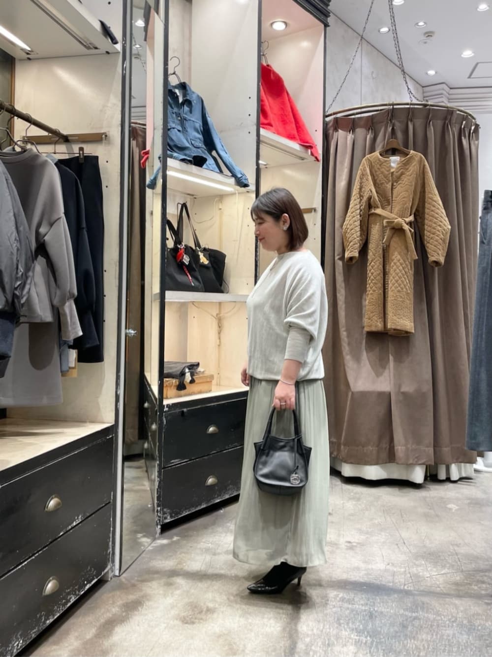 グレー系のニット/セーター、グリーン系のその他パンツ、ブラック系のトートバッグを着用したレディースの冬コーディネートの2枚目の写真