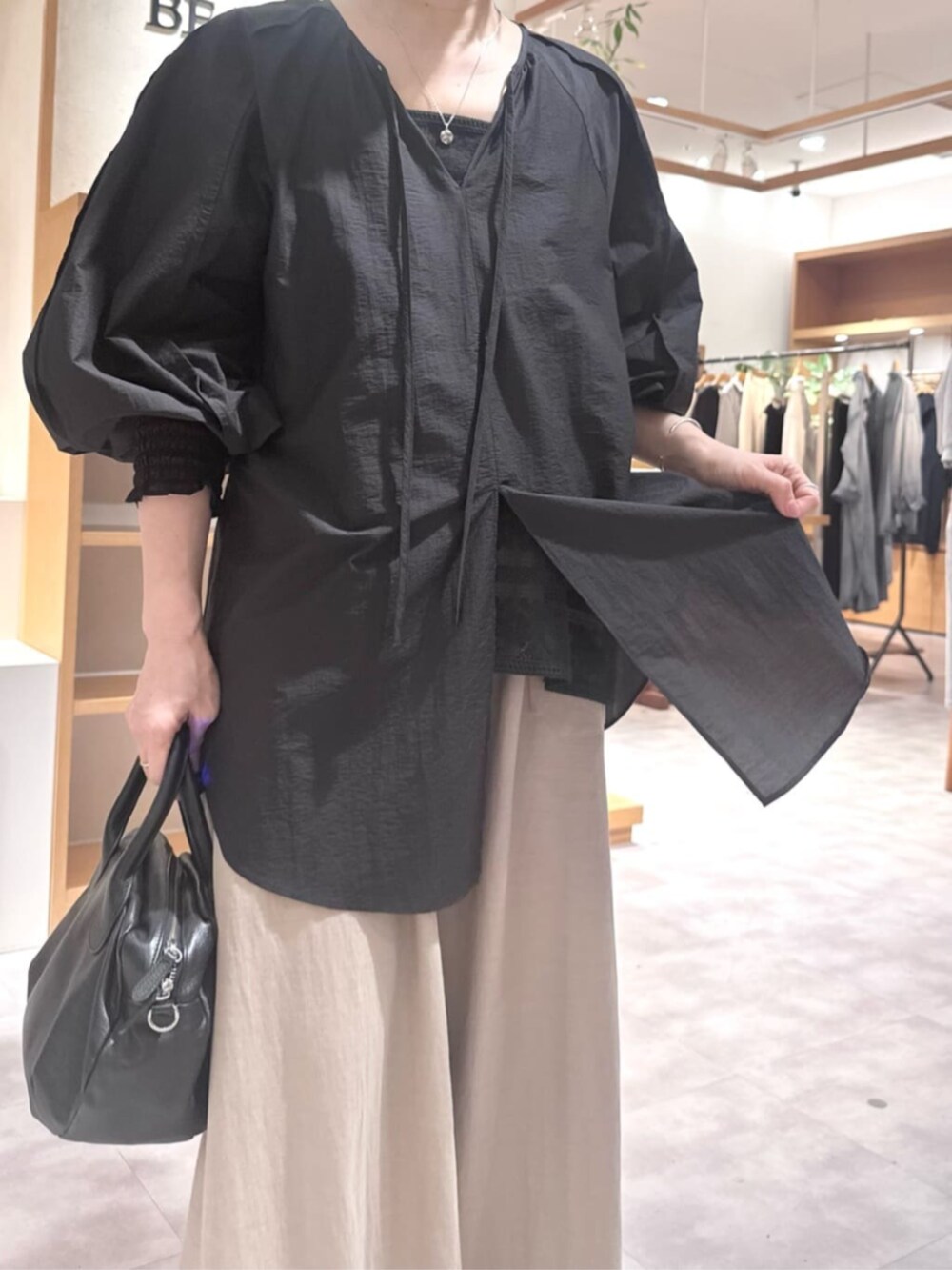 ブラック系のボストンバッグ、ベージュ系のその他パンツ、ブラック系のシャツ/ブラウスを着用したレディースの春コーディネートの9枚目の写真