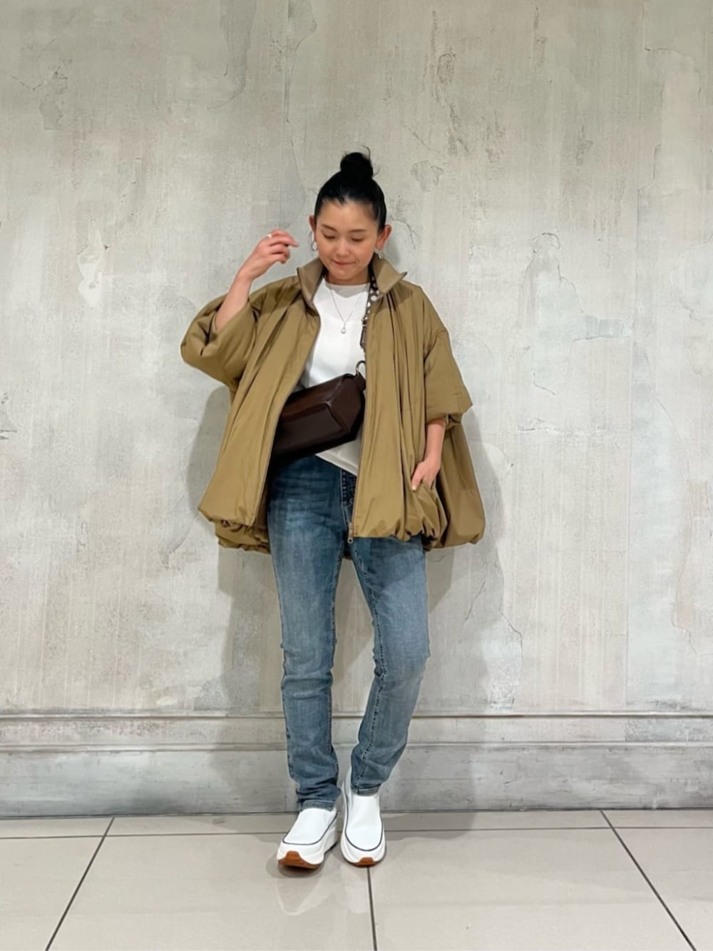 ホワイト系のスニーカー、ブルー系のデニムパンツ、イエロー系のその他アウターを着用したレディースの冬コーディネートの3枚目の写真