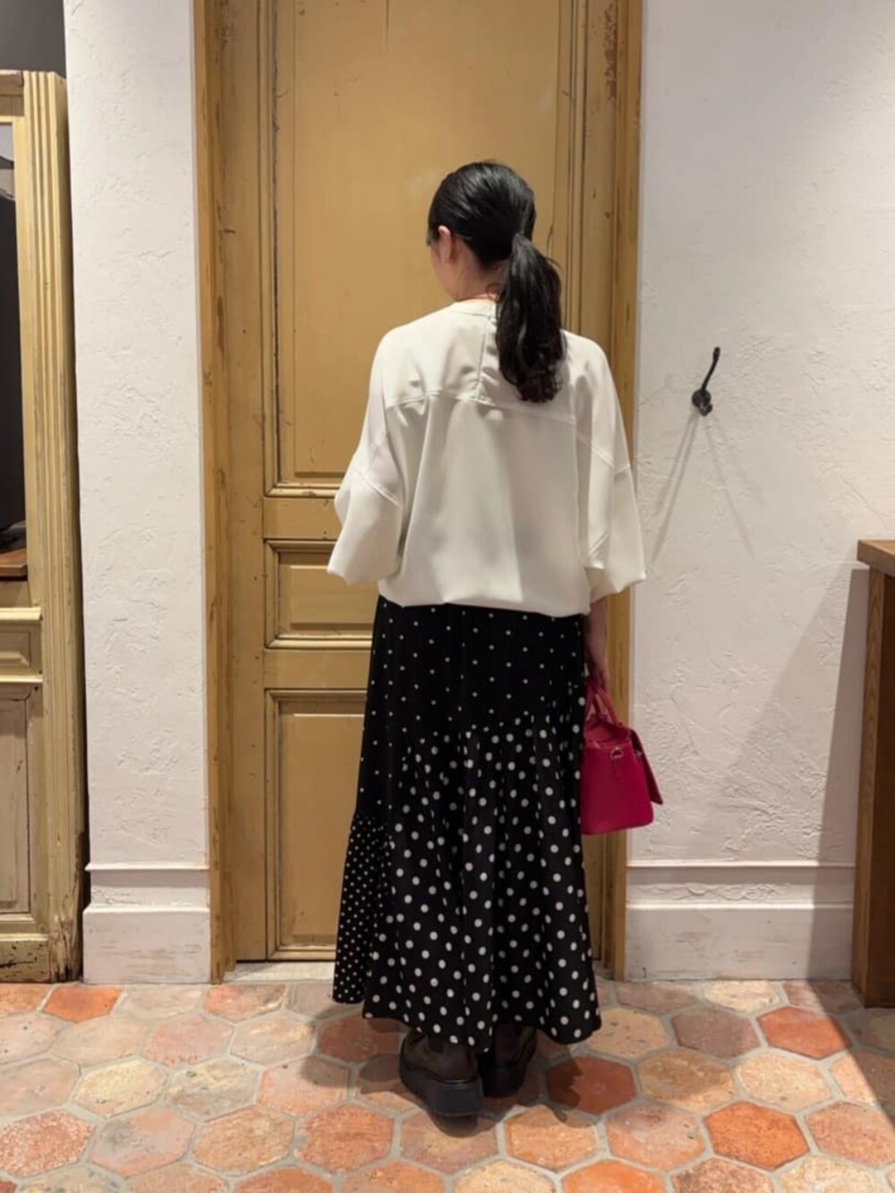 ブラック系のスカート、ピンク系のハンドバッグ、ホワイト系のシャツ/ブラウスを着用したレディースの冬コーディネートの2枚目の写真