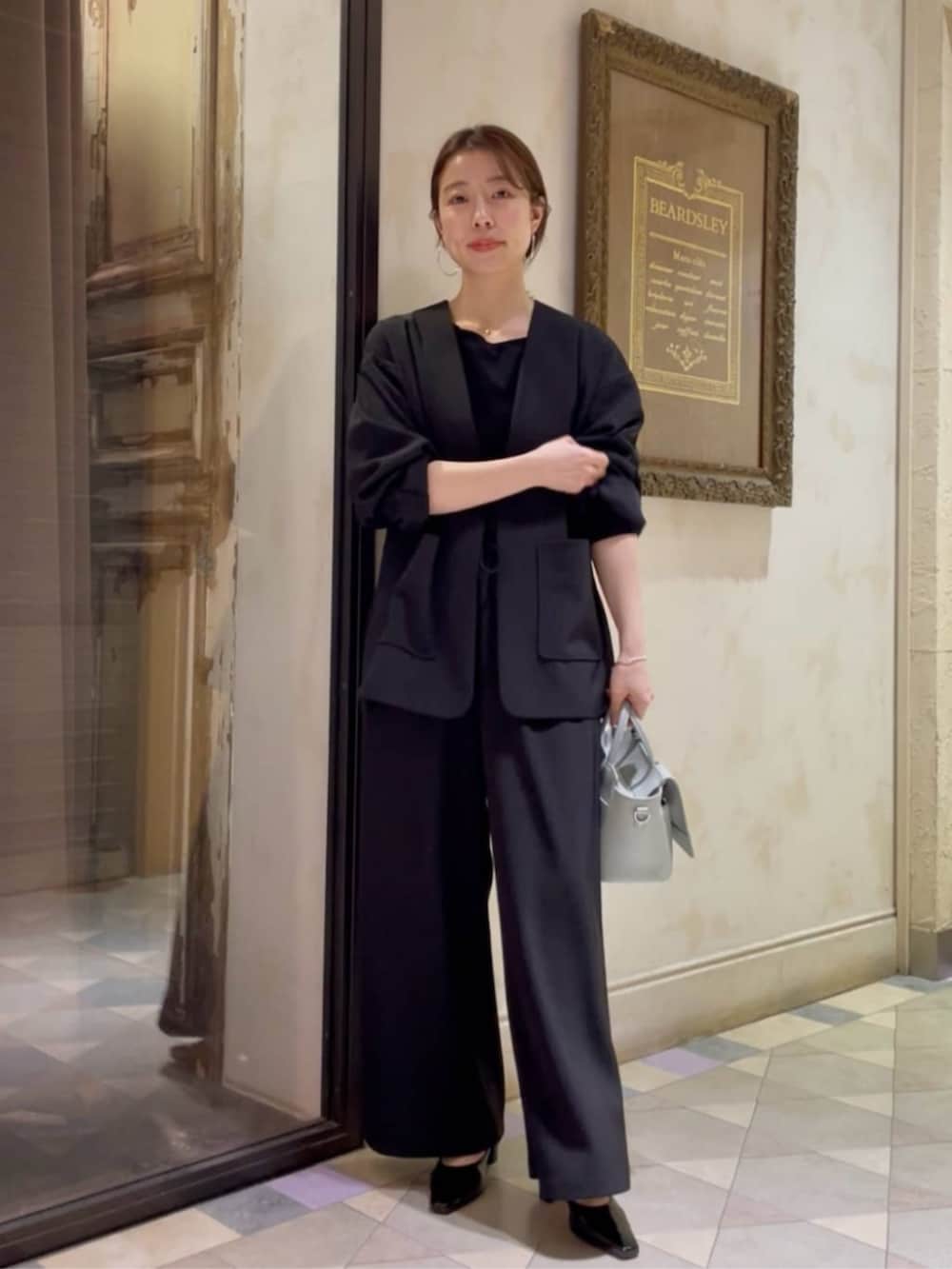 グリーン系のハンドバッグ、ブラック系のその他アウター、ブラック系のその他パンツを着用したレディースの冬コーディネートの3枚目の写真