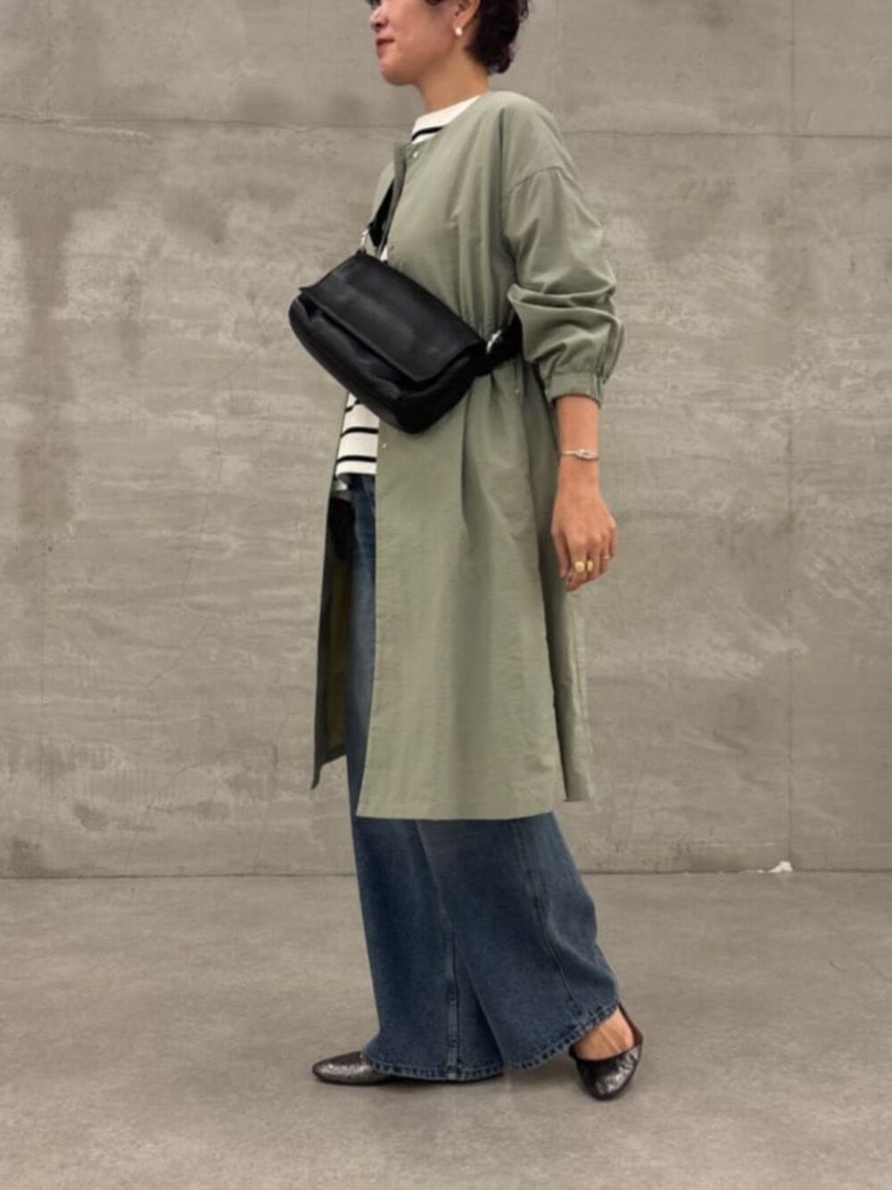 ブラック系のショルダーバッグ、グリーン系のその他アウター、ホワイト系のニット/セーターを着用したレディースの冬コーディネートの2枚目の写真