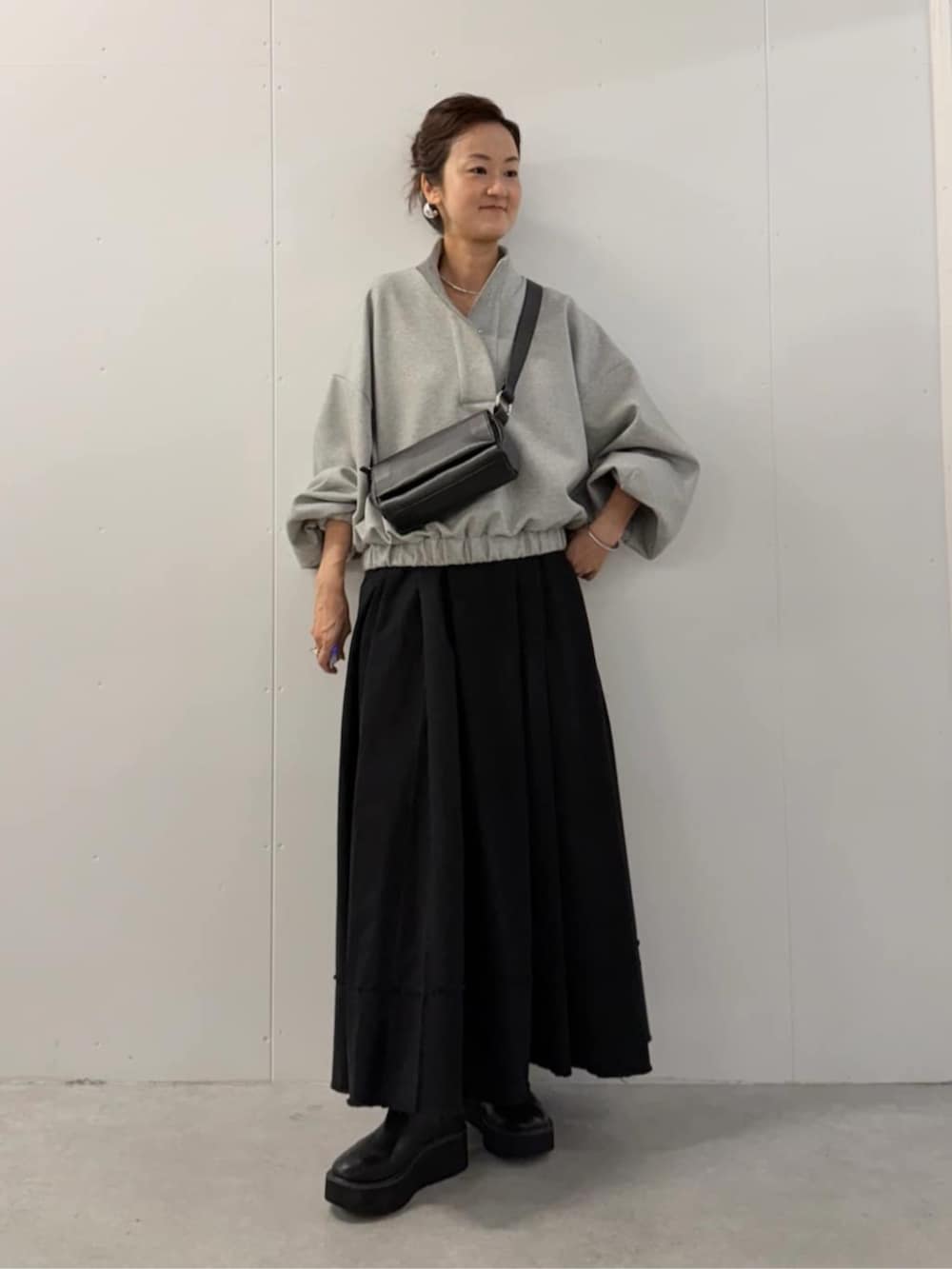 ブラック系のショルダーバッグ、ブラック系のスカート、グレー系のTシャツ/カットソーを着用したレディースの夏コーディネートの4枚目の写真