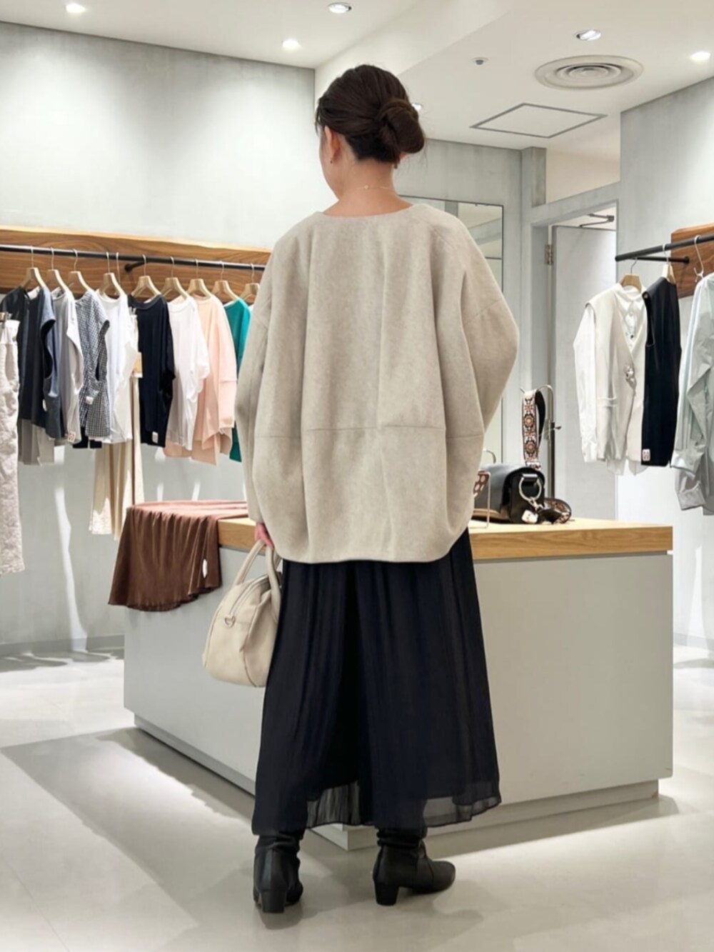 グレー系のノーカラーコート、ベージュ系のニット/セーター、ブラック系のその他パンツを着用したレディースの秋コーディネートの2枚目の写真
