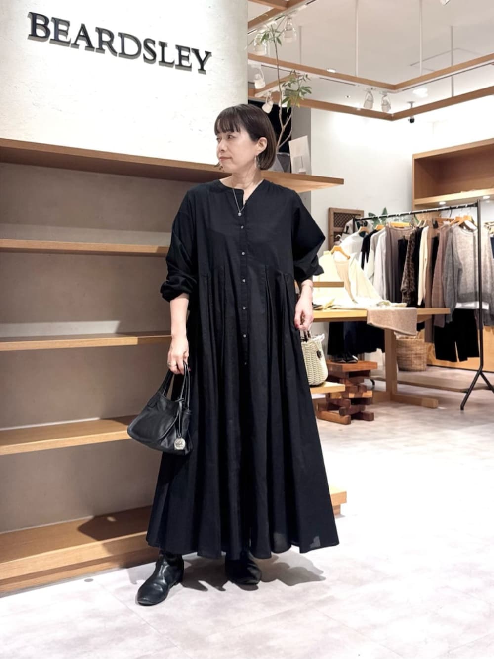 ブルー系のデニムパンツ、イエロー系のトートバッグ、ブラック系のワンピースを着用したレディースの冬コーディネートの7枚目の写真