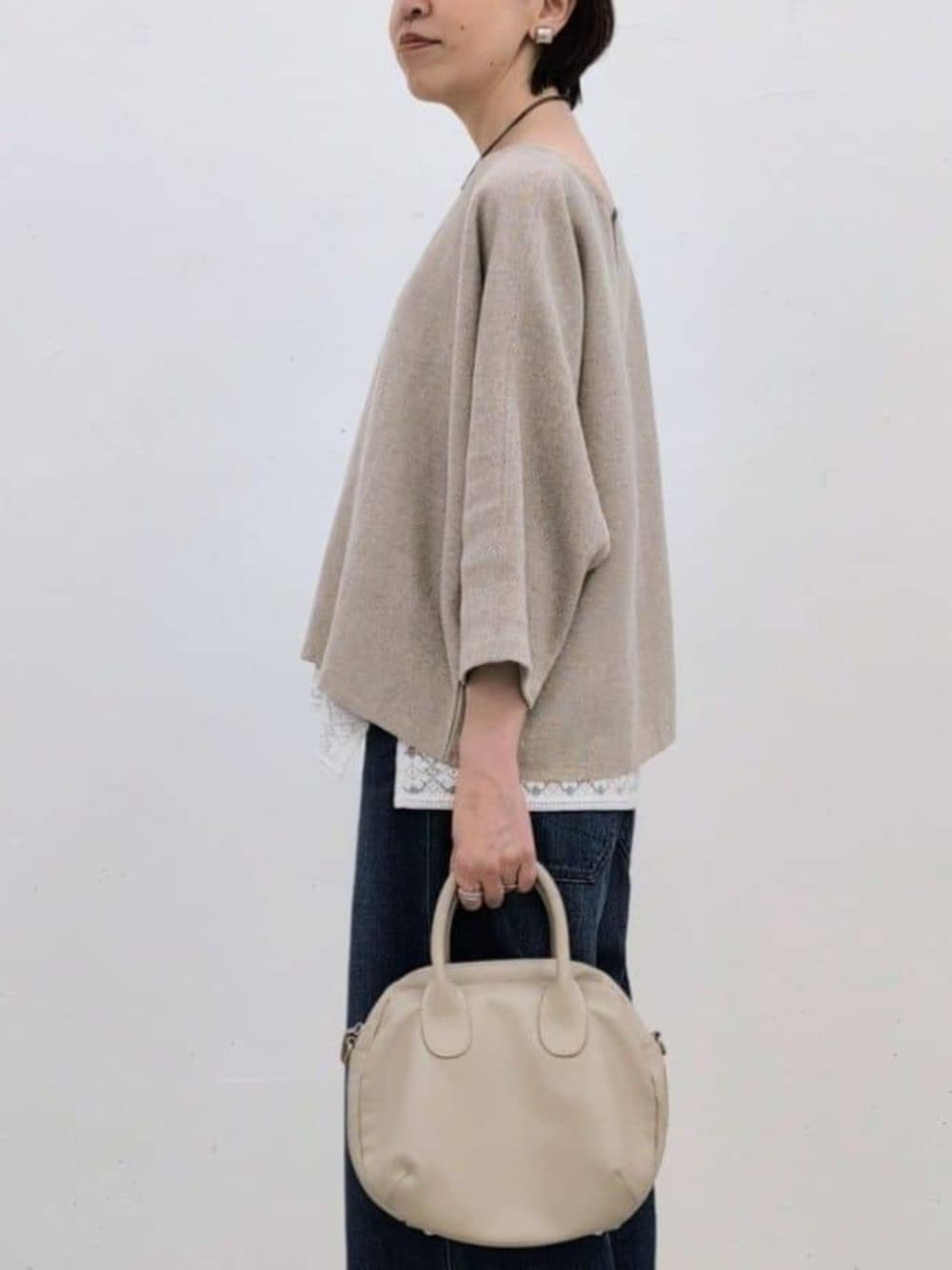 グレー系のボストンバッグ、ホワイト系のシャツ/ブラウス、ベージュ系のニット/セーターを着用したレディースの春コーディネートの5枚目の写真