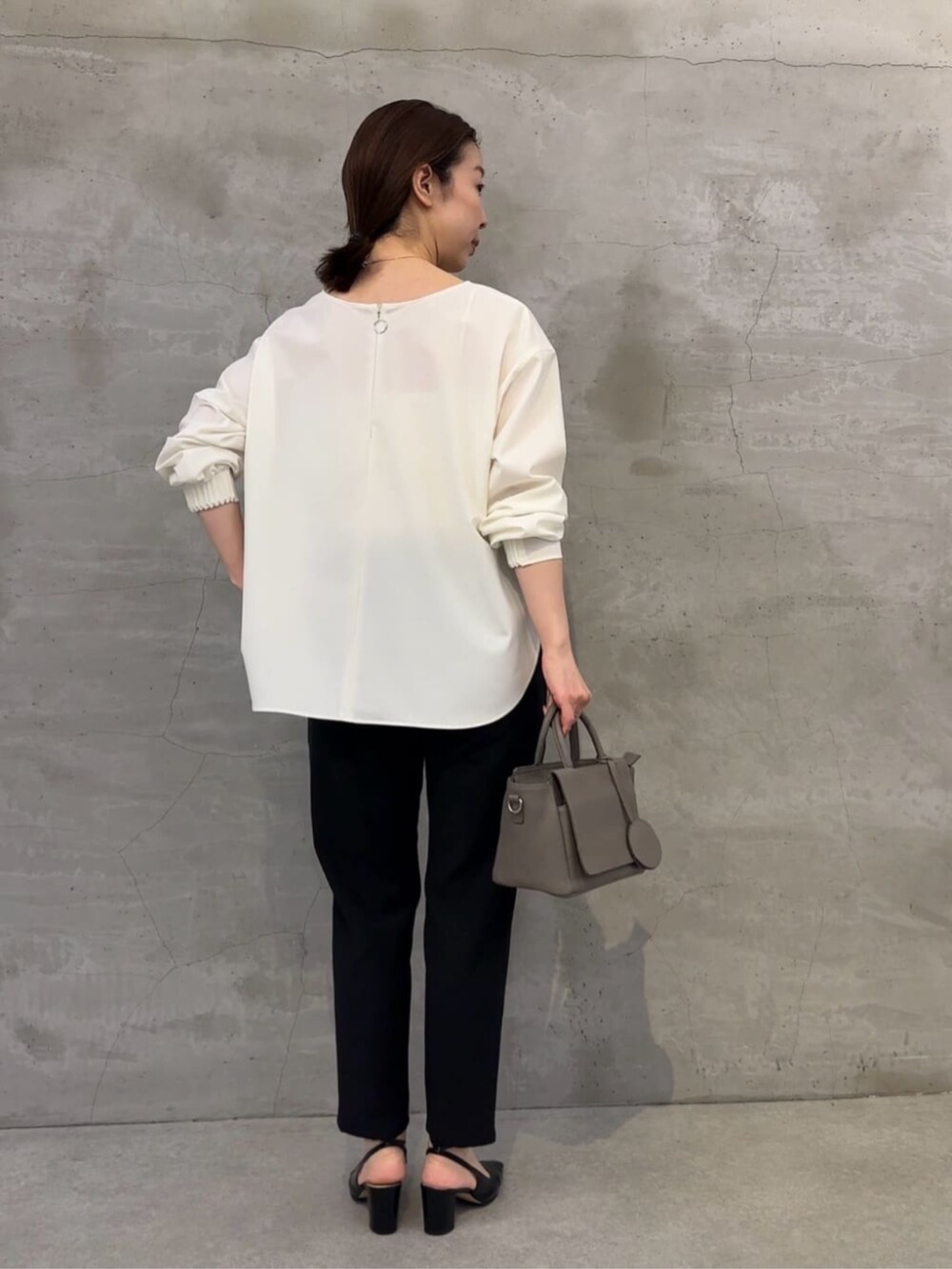 グレー系のハンドバッグ、ブラック系のその他パンツ、ホワイト系のシャツ/ブラウスを着用したレディースの冬コーディネートの2枚目の写真