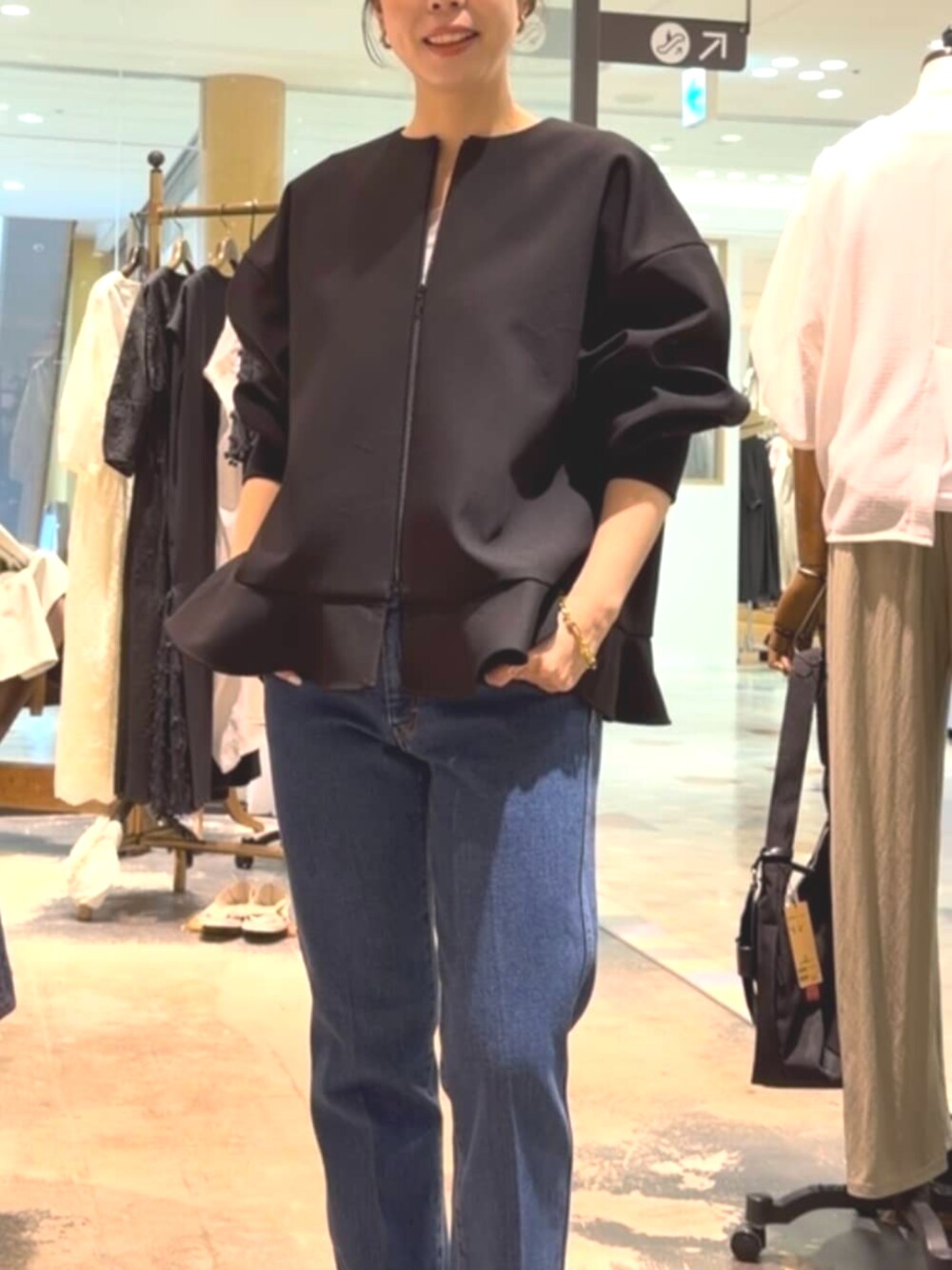 ブラック系のトートバッグ、ブラック系のブルゾン、ブルー系のデニムパンツを着用したレディースの夏コーディネートの6枚目の写真