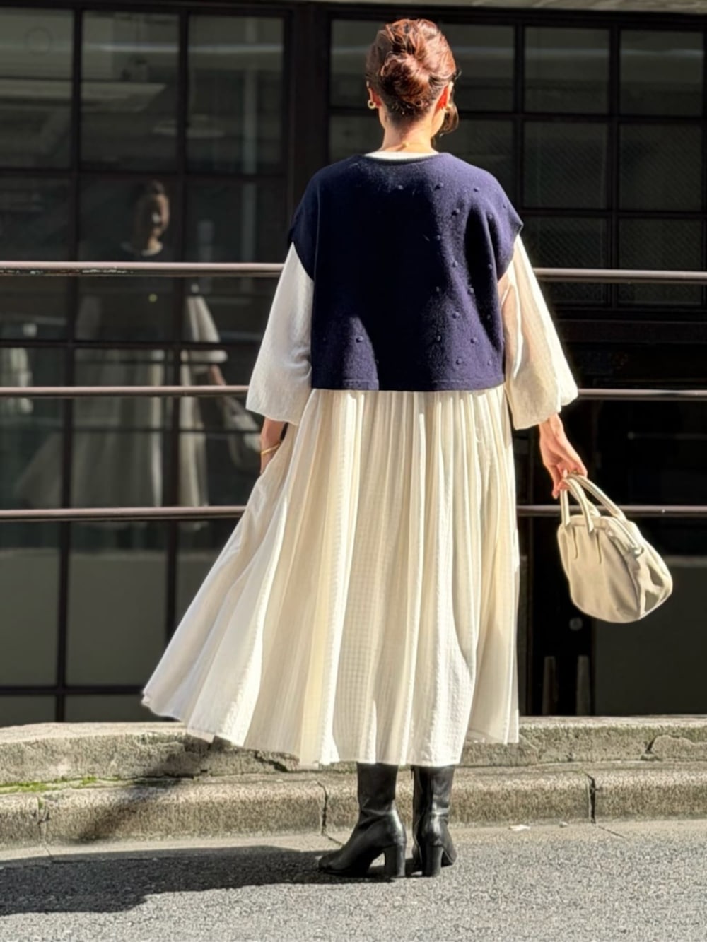 ホワイト系のワンピース、ブラック系のブーツ、ブルー系のベストを着用したレディースの秋コーディネートの4枚目の写真
