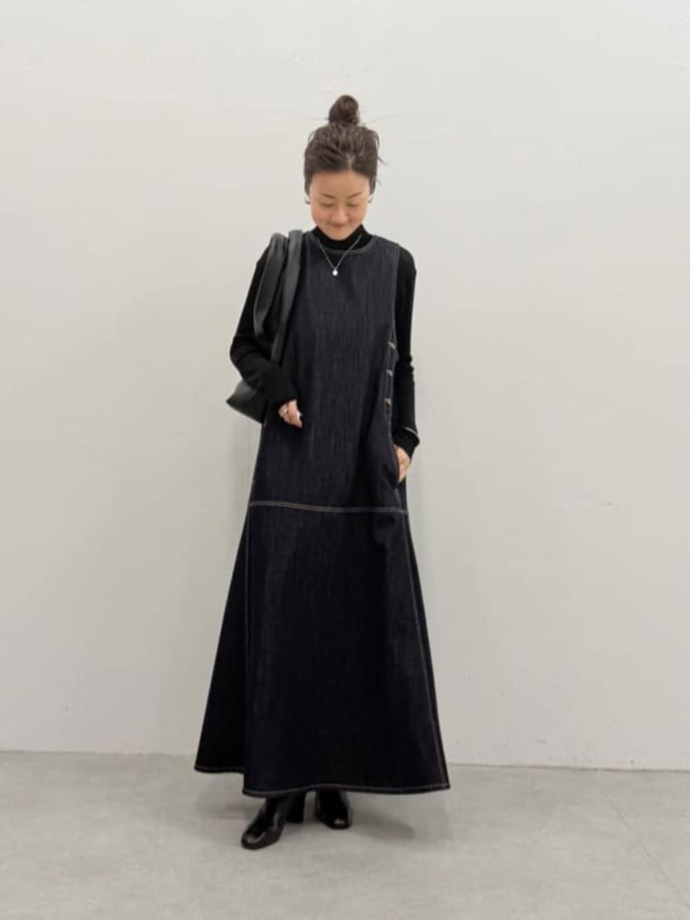ブラック系のニット/セーター、ブルー系のワンピース、ブラック系のトートバッグを着用したレディースの夏コーディネートの2枚目の写真