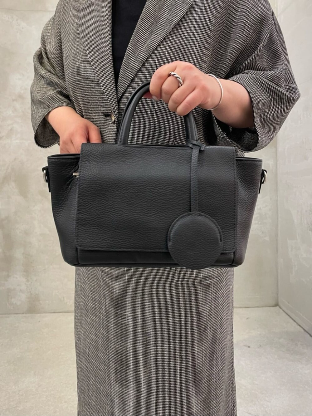 ブラック系のハンドバッグ、ベージュ系のテーラードジャケット、ベージュ系のスカートを着用したレディースの春コーディネートの6枚目の写真