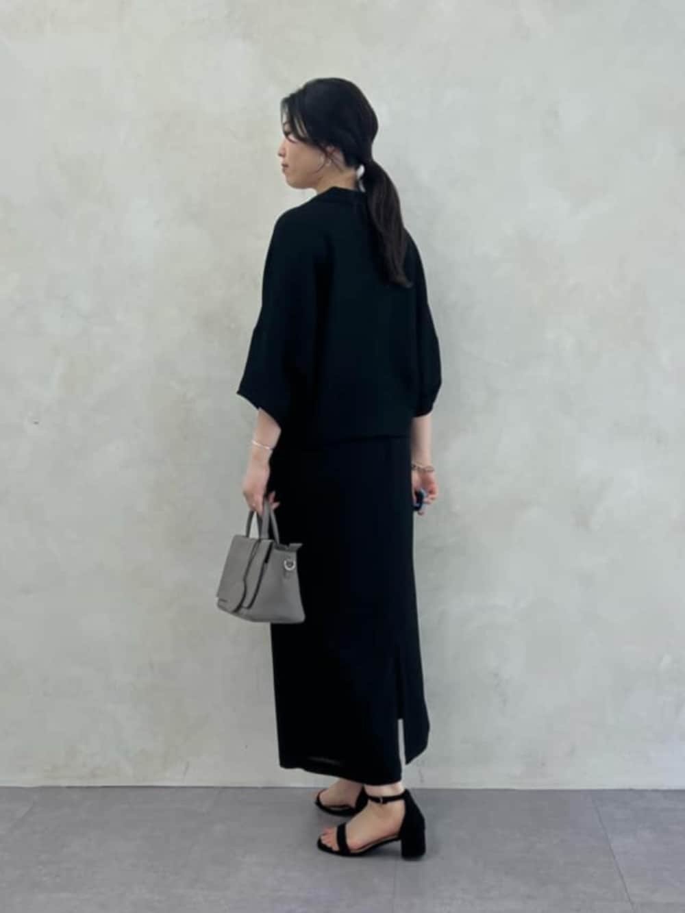 グレー系のハンドバッグ、ブラック系のテーラードジャケット、ブラック系のスカートを着用したレディースの春コーディネートの3枚目の写真