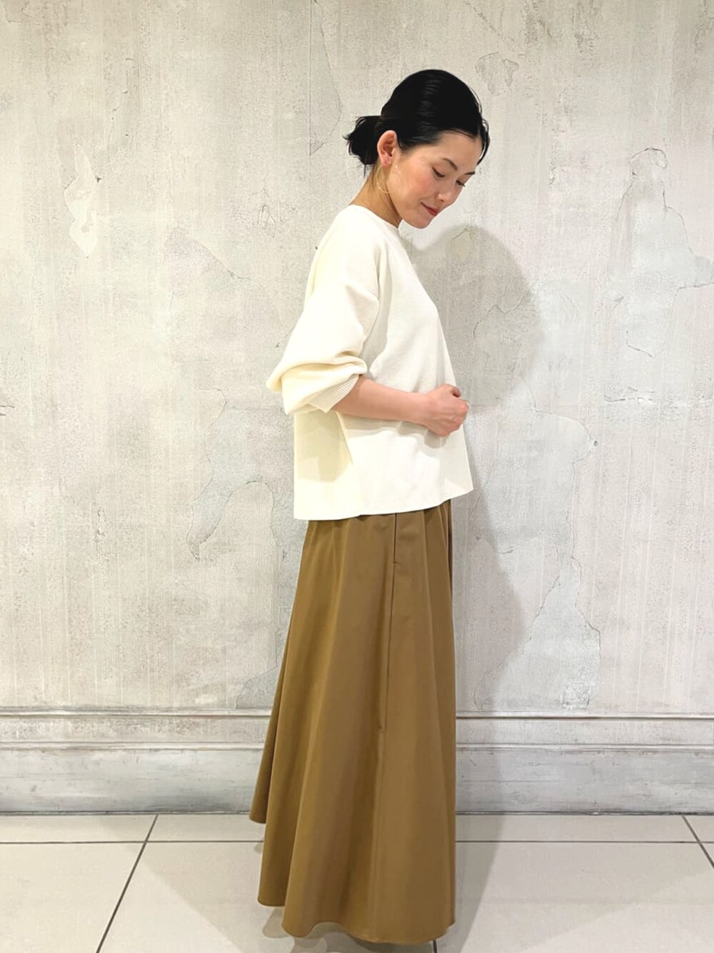 イエロー系のスカート、ホワイト系のニット/セーター、ベージュ系のバレエシューズを着用したレディースの冬コーディネートの3枚目の写真