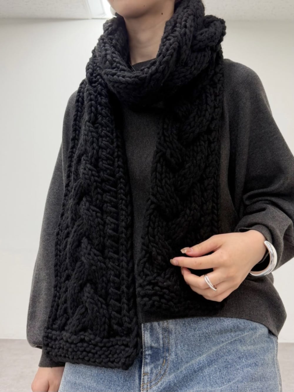 グレー系のニット/セーター、ブルー系のデニムパンツ、ブラック系のマフラーを着用したレディースの秋コーディネートの3枚目の写真