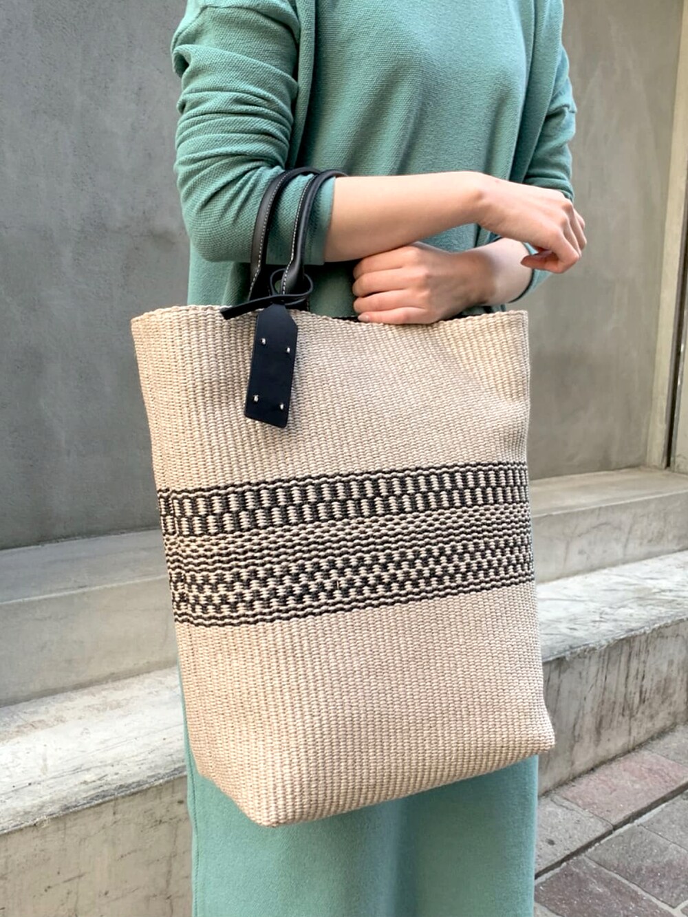 ブラック系のトートバッグ、グリーン系のニット/セーター、ホワイト系のその他パンツを着用したレディースの春コーディネートの3枚目の写真