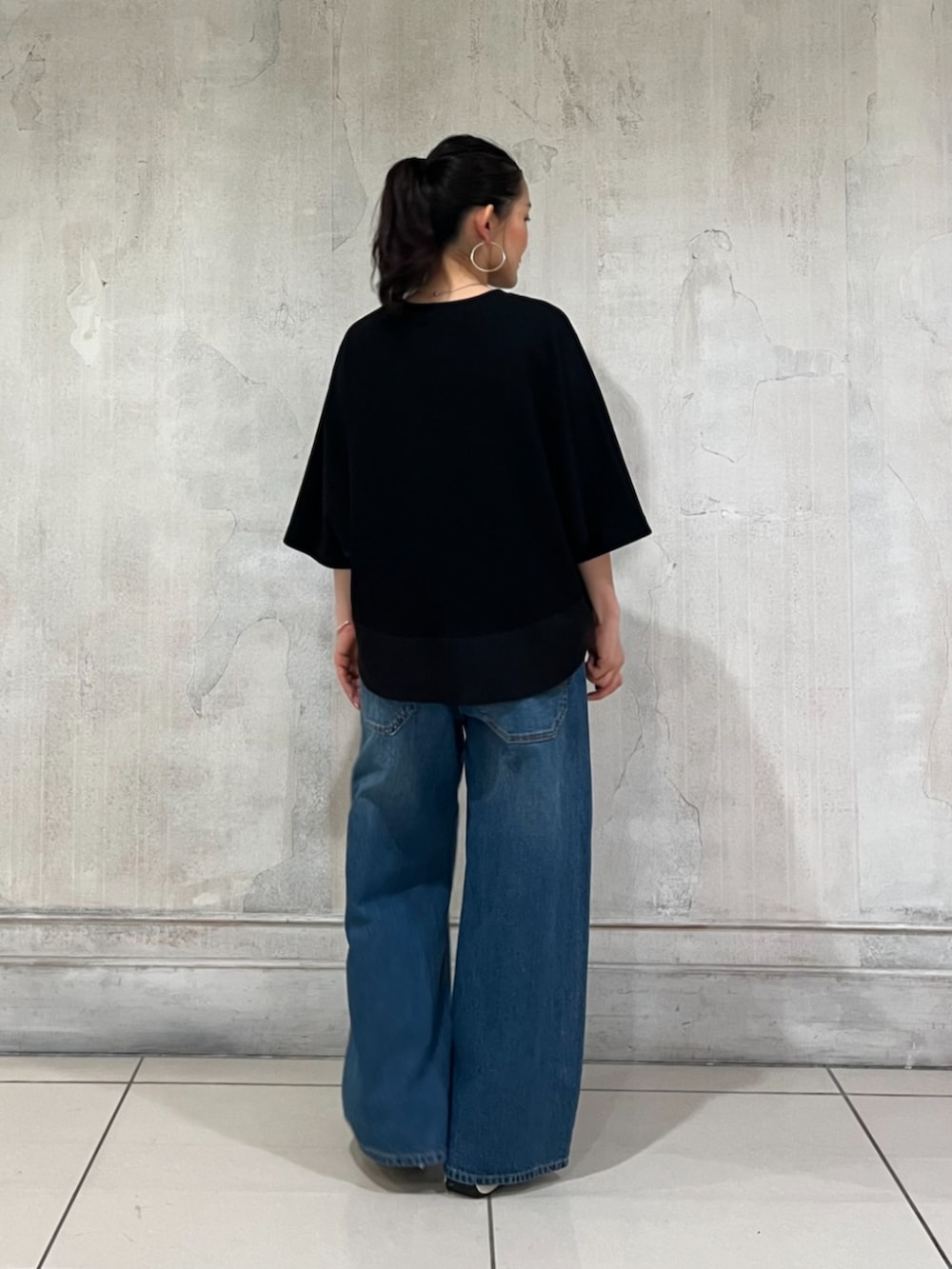 ブルー系のその他パンツ、ブラック系のTシャツ/カットソー、ホワイト系のスニーカーを着用したレディースの春コーディネートの4枚目の写真