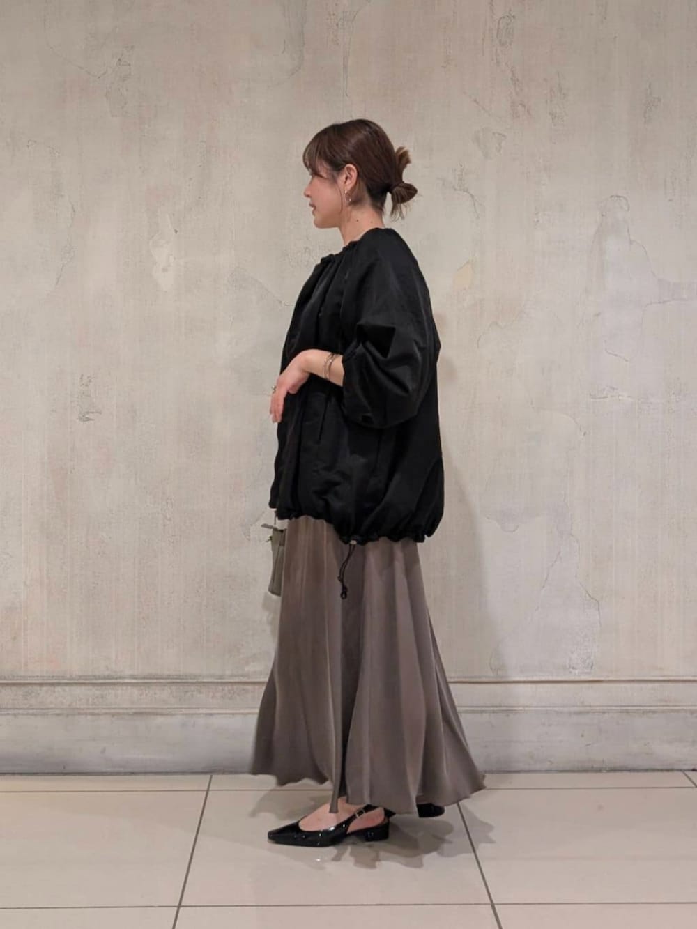 グリーン系のスカート、グレー系のハンドバッグ、ブラック系のノーカラージャケットを着用したレディースの春コーディネートの4枚目の写真