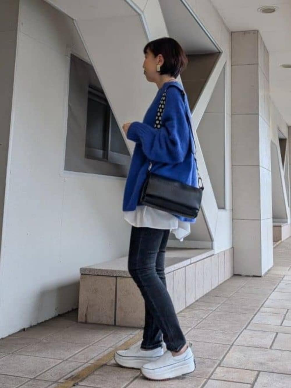 ホワイト系のTシャツ/カットソー、ホワイト系のスニーカー、ブルー系のニット/セーターを着用したレディースの冬コーディネートの4枚目の写真