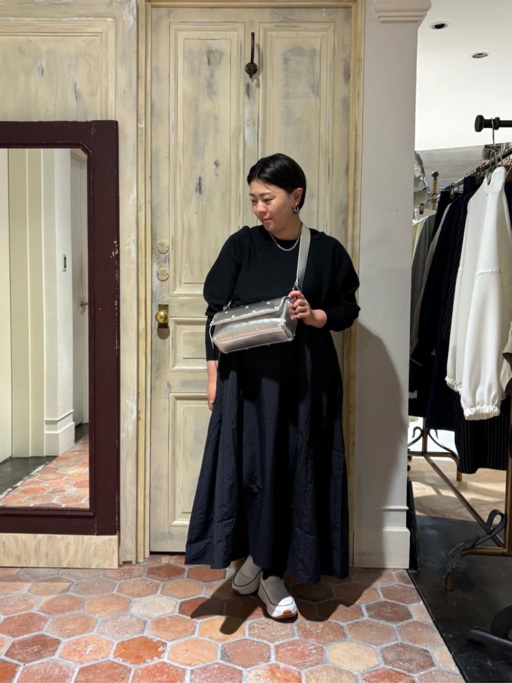 ホワイト系のスニーカー、ブラック系のワンピース、シルバー系のショルダーバッグを着用したレディースの冬コーディネートの2枚目の写真