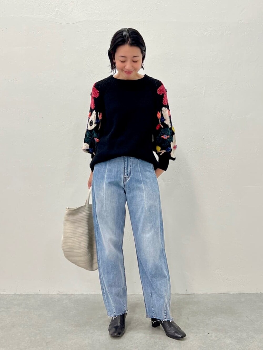 ブラック系のニット/セーター、ブルー系のデニムパンツを着用したレディースの夏コーディネートの2枚目の写真
