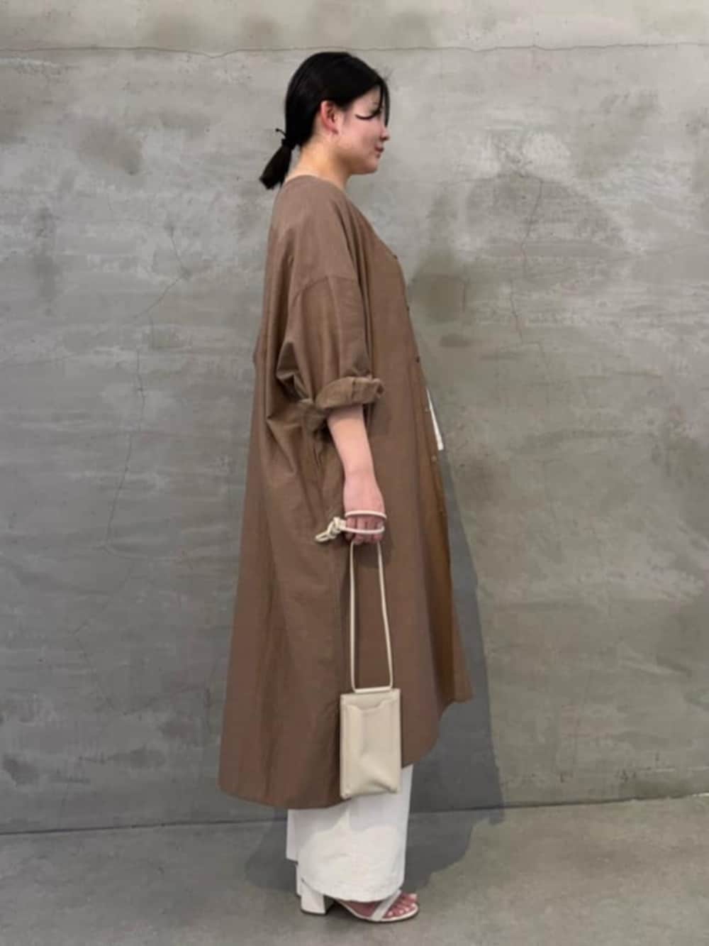 ホワイト系のショルダーバッグ、ホワイト系のシャツ/ブラウス、ベージュ系のワンピースを着用したレディースの冬コーディネートの4枚目の写真