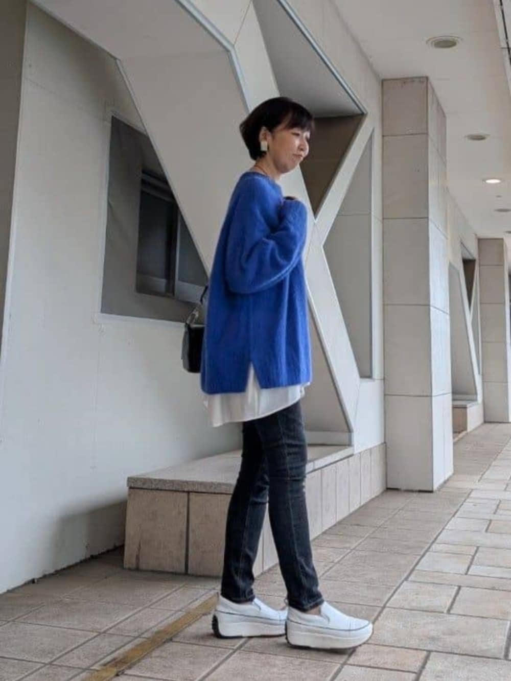 ホワイト系のTシャツ/カットソー、ホワイト系のスニーカー、ブルー系のニット/セーターを着用したレディースの冬コーディネートの2枚目の写真