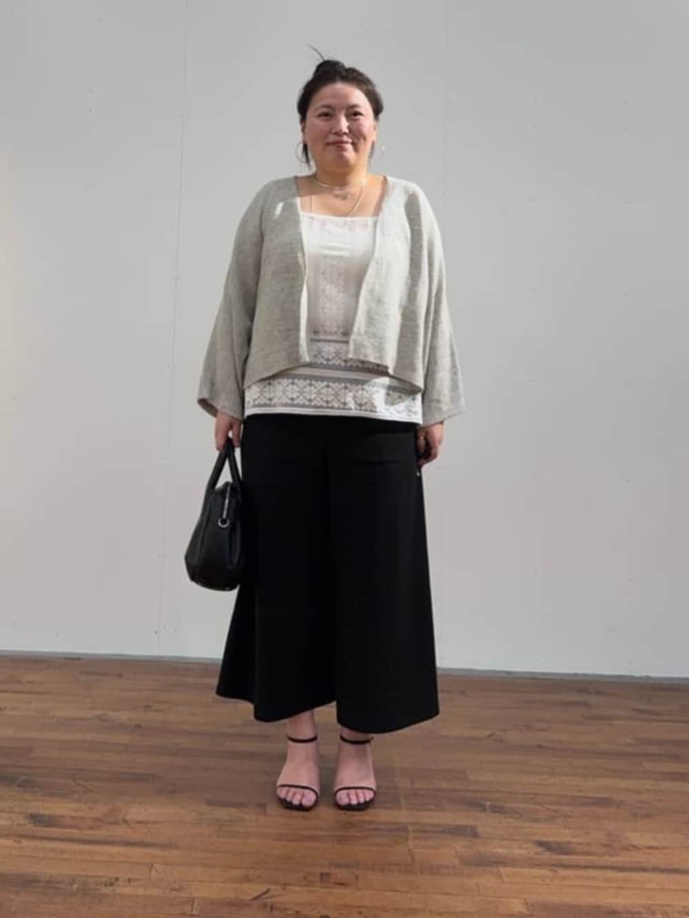 ブラック系のボストンバッグ、ホワイト系のシャツ/ブラウス、グレー系のカーディガン/ボレロを着用したレディースの春コーディネートの2枚目の写真