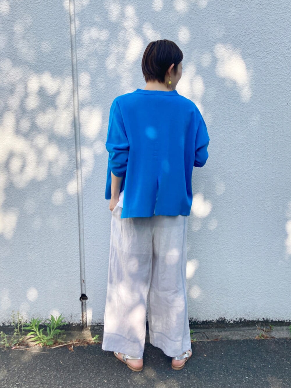 グレー系のその他パンツ、ホワイト系のTシャツ/カットソー、シルバー系のサンダルを着用したレディースの春コーディネートの2枚目の写真