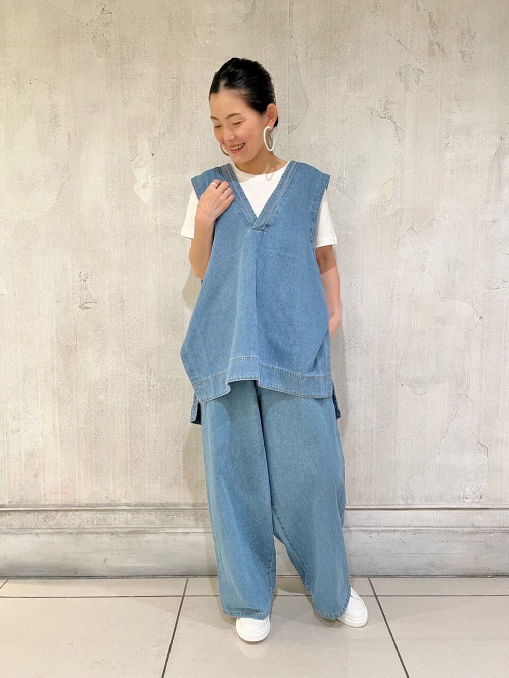 ブルー系のベスト、ホワイト系のTシャツ/カットソー、ブルー系のデニムパンツを着用したレディースの夏コーディネートの2枚目の写真