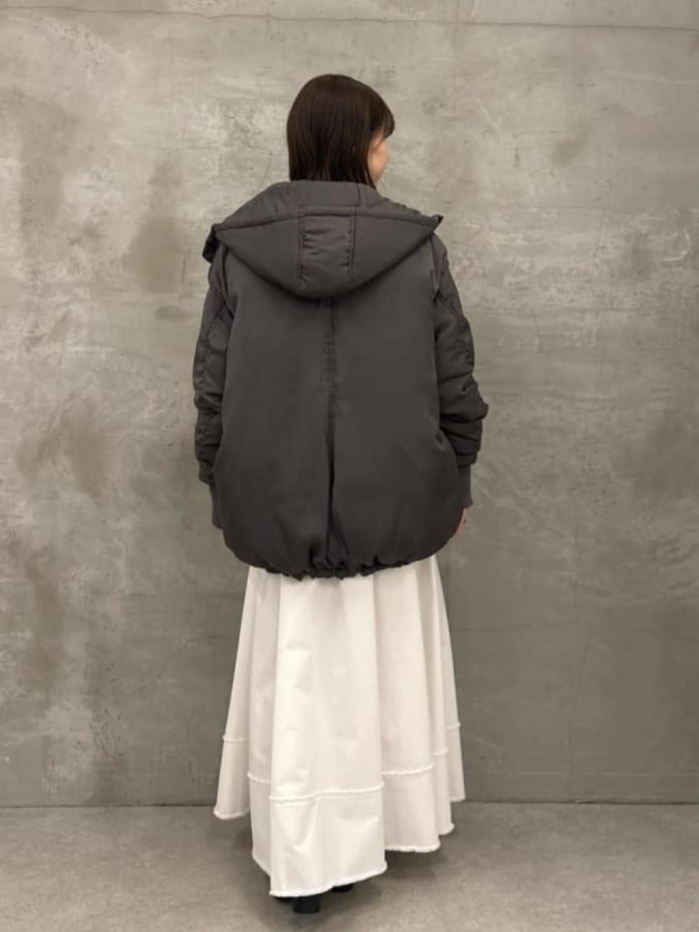 ホワイト系のスカート、グレー系のダウンジャケット/コート、グレー系のTシャツ/カットソーを着用したレディースの秋コーディネートの7枚目の写真