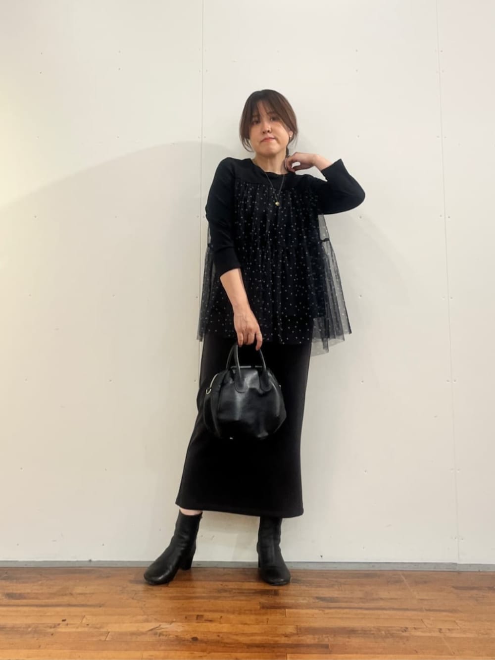ブラック系のボストンバッグ、グレー系のスカート、ブラック系のTシャツ/カットソーを着用したレディースの夏コーディネートの2枚目の写真