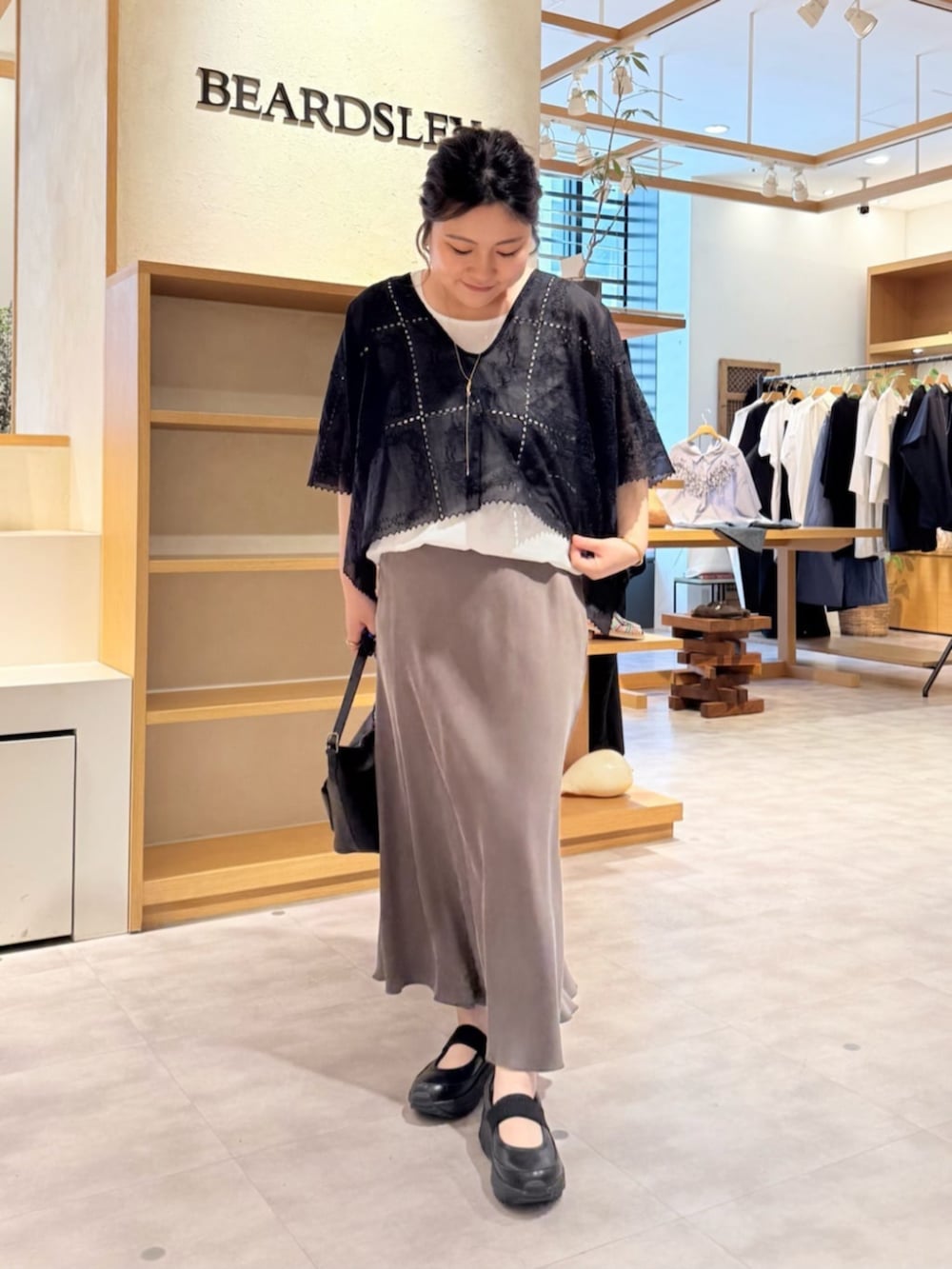 グリーン系のスカート、ブラック系のシャツ/ブラウス、ブラック系のスニーカーを着用したレディースの春コーディネートの4枚目の写真