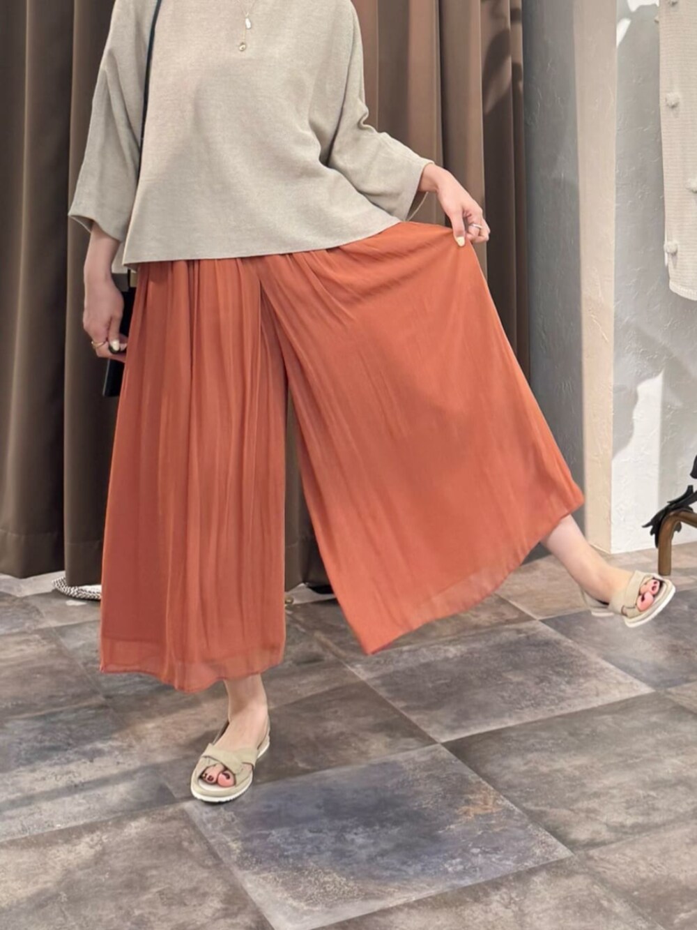オレンジ系のその他パンツ、ベージュ系のニット/セーターを着用したレディースの春コーディネートの9枚目の写真
