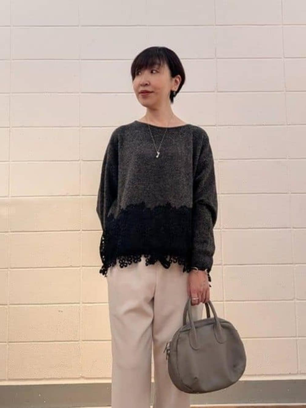 グレー系のトートバッグ、グレー系のニット/セーター、ホワイト系のその他パンツを着用したレディースの秋コーディネートの2枚目の写真