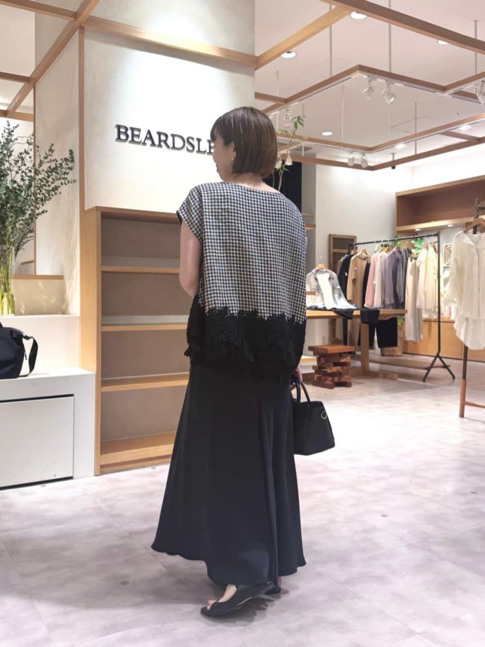 ブラック系のスカート、ブラック系のハンドバッグ、ブラック系のシャツ/ブラウスを着用したレディースの春コーディネートの4枚目の写真