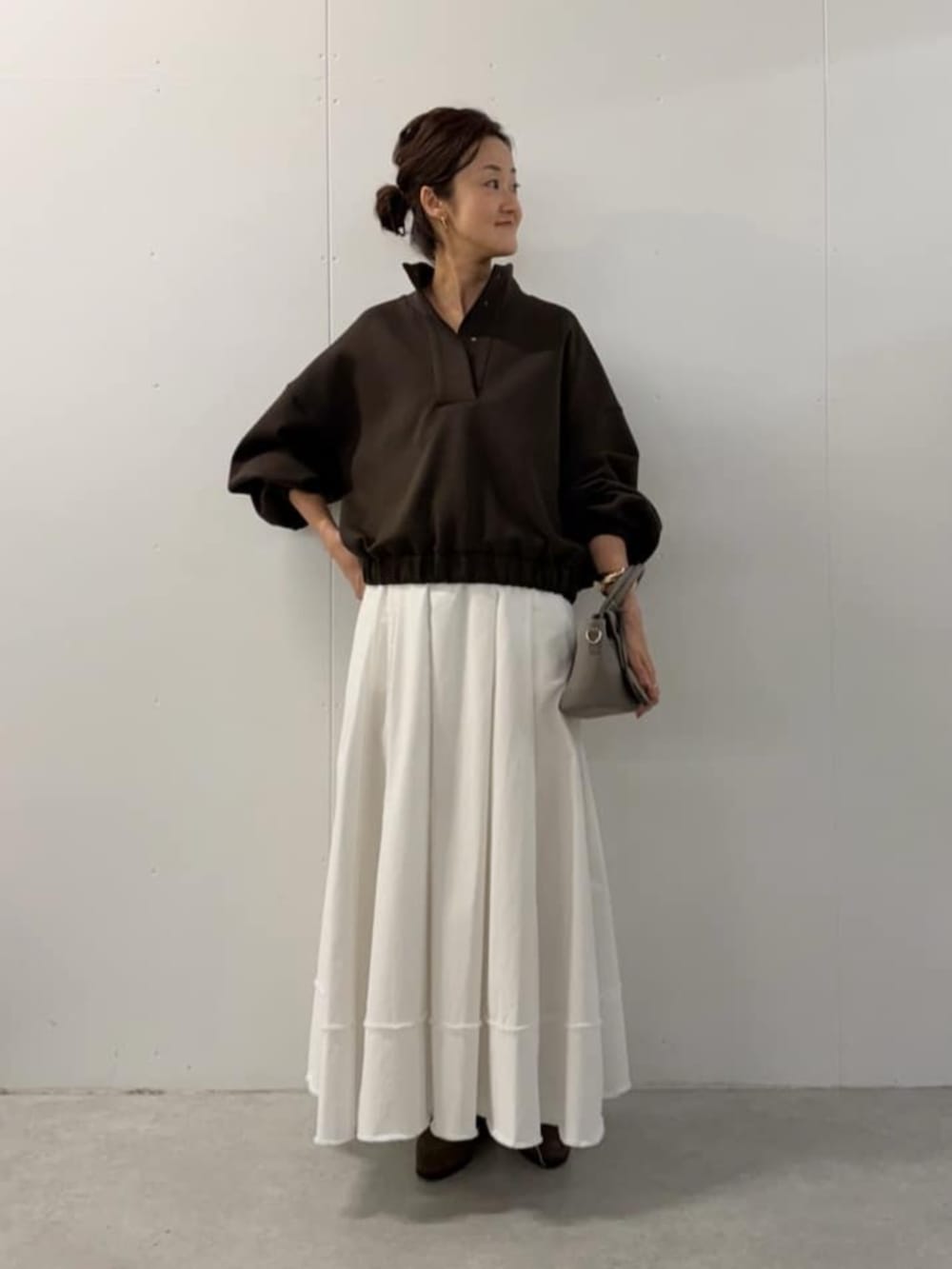 グレー系のハンドバッグ、ホワイト系のスカート、ブラウン系のTシャツ/カットソーを着用したレディースの夏コーディネートの7枚目の写真