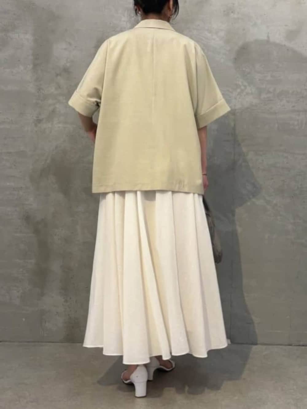 グレー系のボストンバッグ、ホワイト系のキャミソール、ベージュ系のテーラードジャケットを着用したレディースの春コーディネートの4枚目の写真