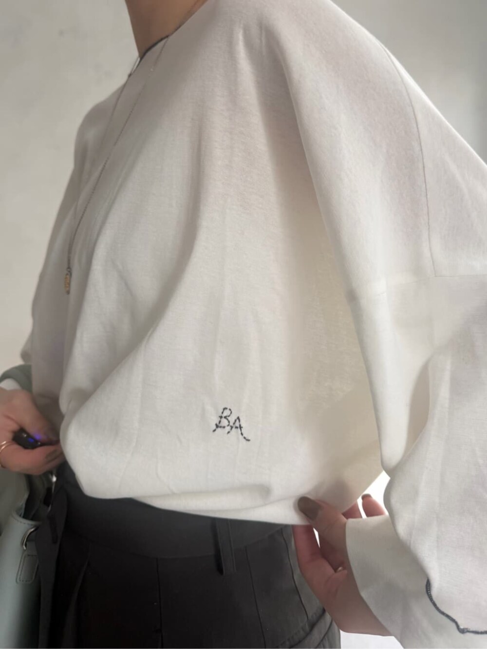 グリーン系のハンドバッグ、グレー系のその他パンツ、ホワイト系のTシャツ/カットソーを着用したレディースの冬コーディネートの6枚目の写真