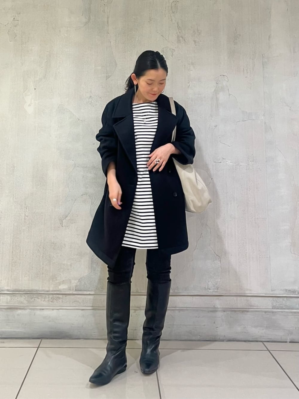 ブルー系のTシャツ/カットソー、ブラック系のデニムパンツ、ブラック系のピーコートを着用したレディースの冬コーディネートの2枚目の写真